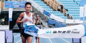 A local man crosses the finishing line ahead of Ethiopian runner Alemtsehay Asefa during the 2022 Taipei City Marathon held on December 18 in Taiwan.