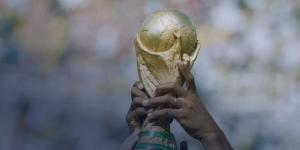 An image showing a couple of hands holding the official FIFA World Cup trophy.