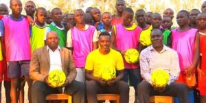 Ex-Harambee Stars player James Situma (sitting at the centre) poses for a photo with students and stakeholders at the Saint Maurice Mwira Secondary School in Kakamega County on February 20, 2023. 