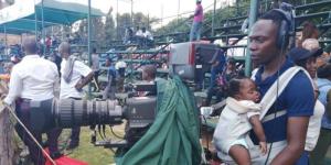 Zimbabwean photographer Mhofuya Soko records a cricket match while carrying her baby on January 15, 2023, at Harare Stadium. 