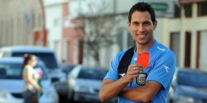 Argentine referee Facundo Tello poses for a photo with a red card in his hand.