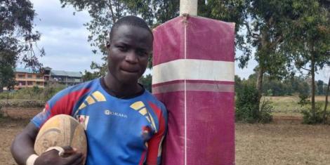 Emmanuel Olume posing with a rugby ball in 2022.
