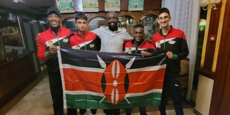 The Kenyan squash team poses for a photo with the countries flag.