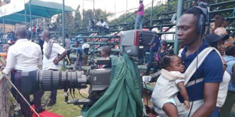 Zimbabwean photographer Mhofuya Soko records a cricket match while carrying her baby on January 15, 2023, at Harare Stadium.