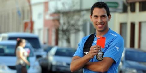 Argentine referee Facundo Tello poses for a photo with a red card in his hand.
