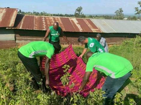 A blanket being spread at the grave by the K'Ogalo technical bench
